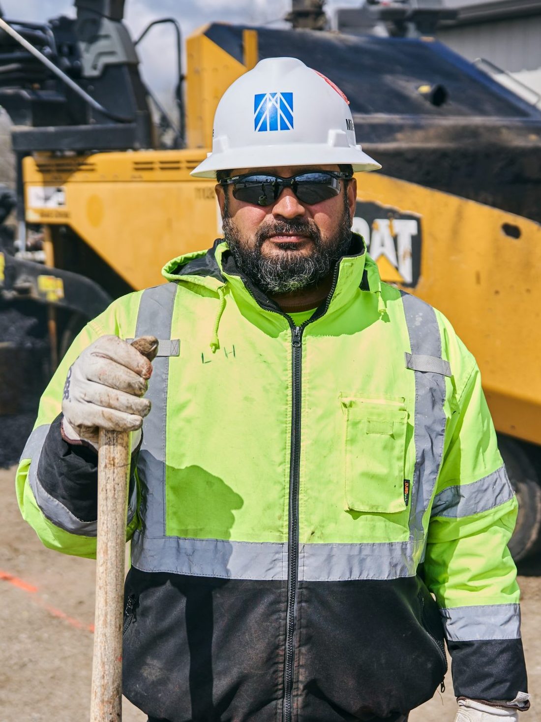 hispanic construction worker on paving crew with a shovel