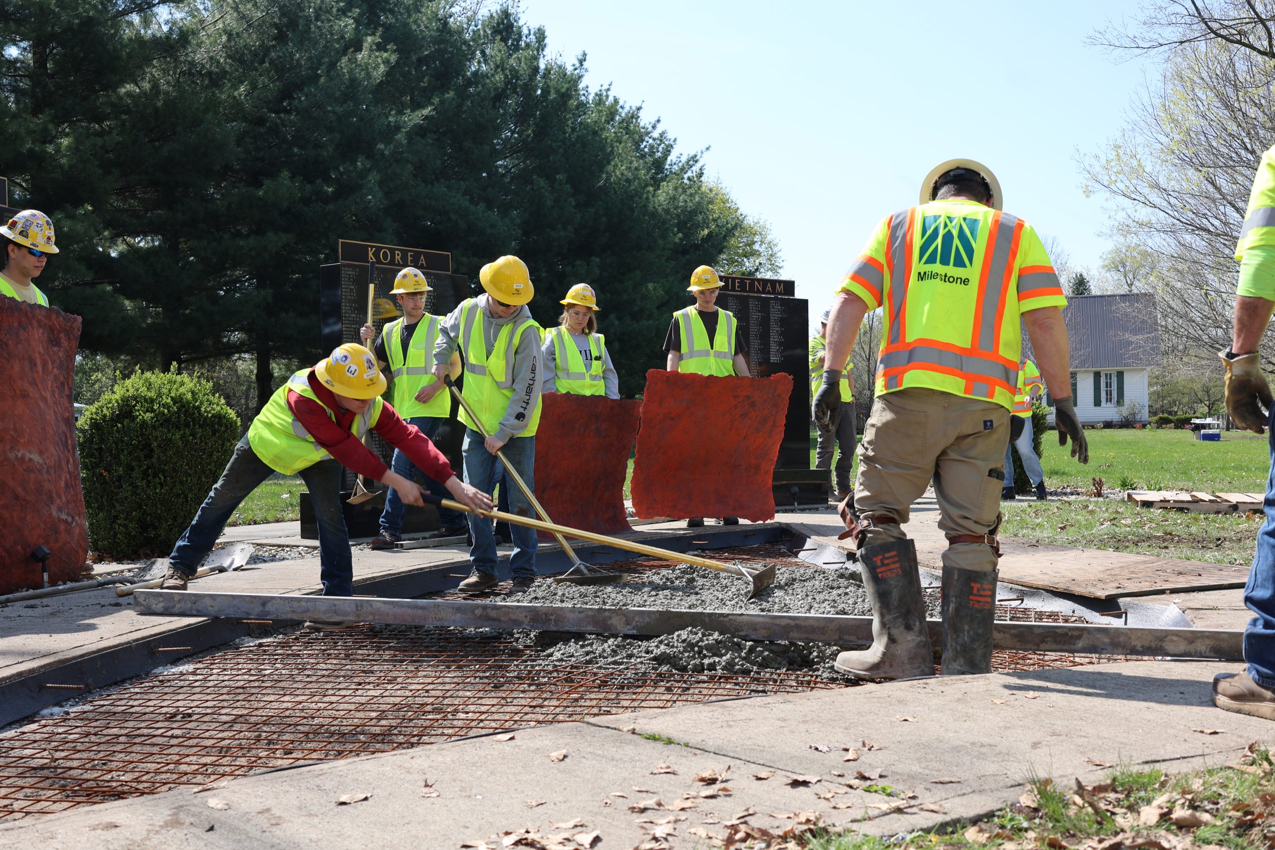 Students pouring concrete to prepare for Veteran memorial